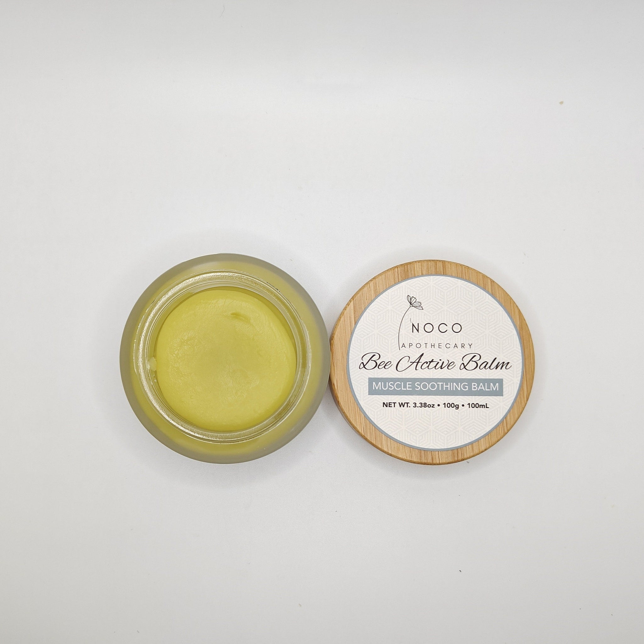 Muscle soothing balm in yellow, glass jar, and wooden lid with text