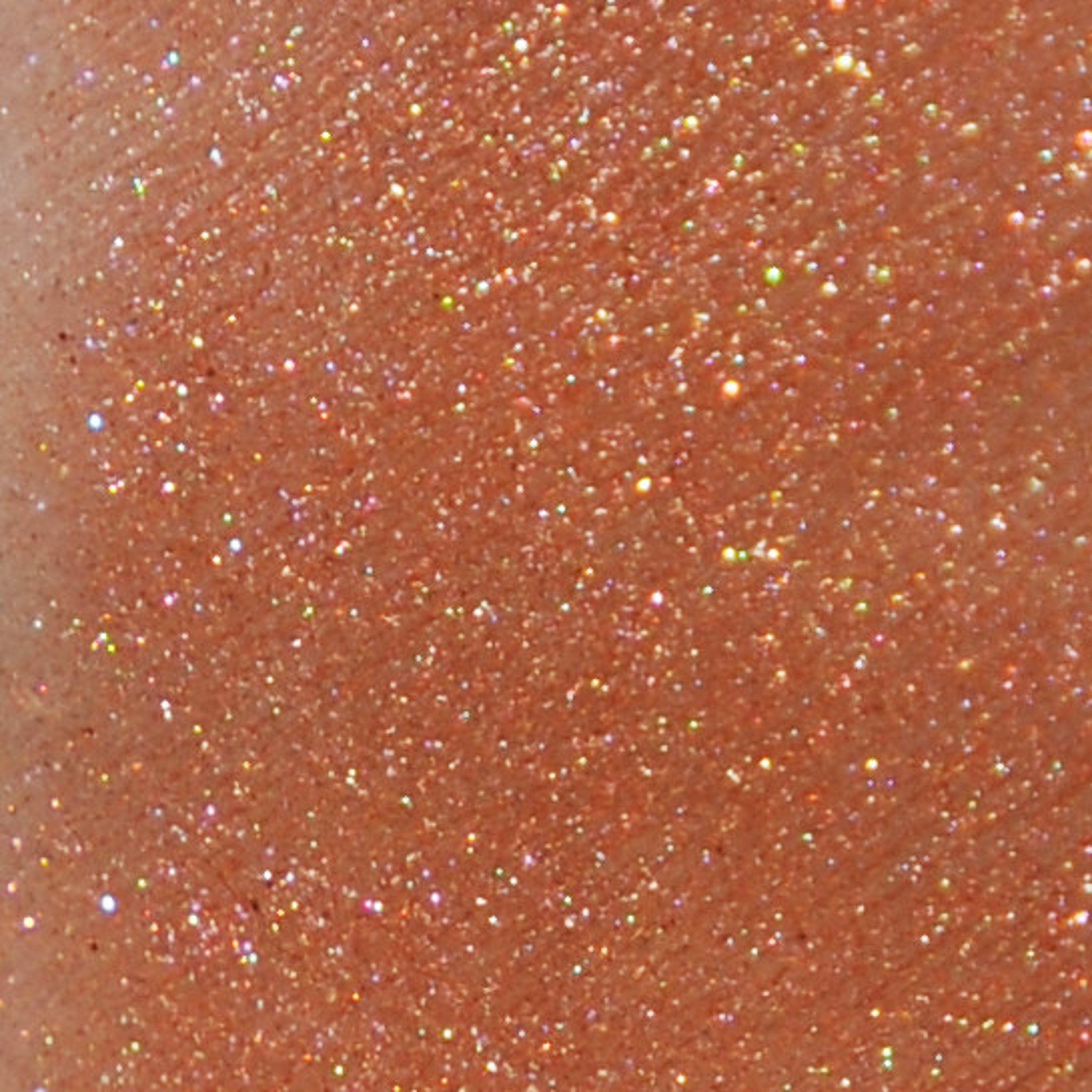 Hand applying shimmery copper mineral eye shadow with a brush from a small jar with sifter