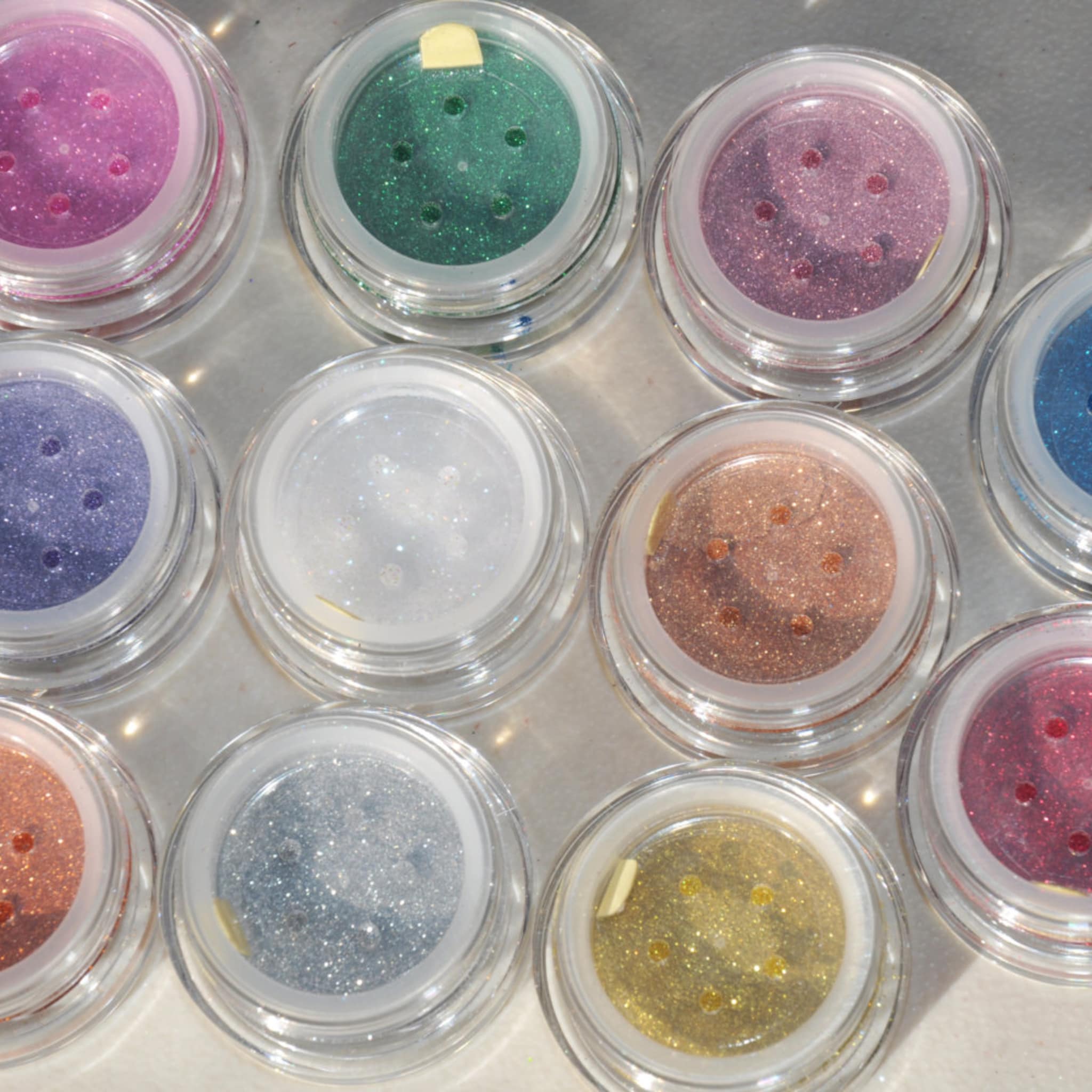 Close-up of Wiggins glitter eye shadow jar with black sifter lid and silver label on sleek white background