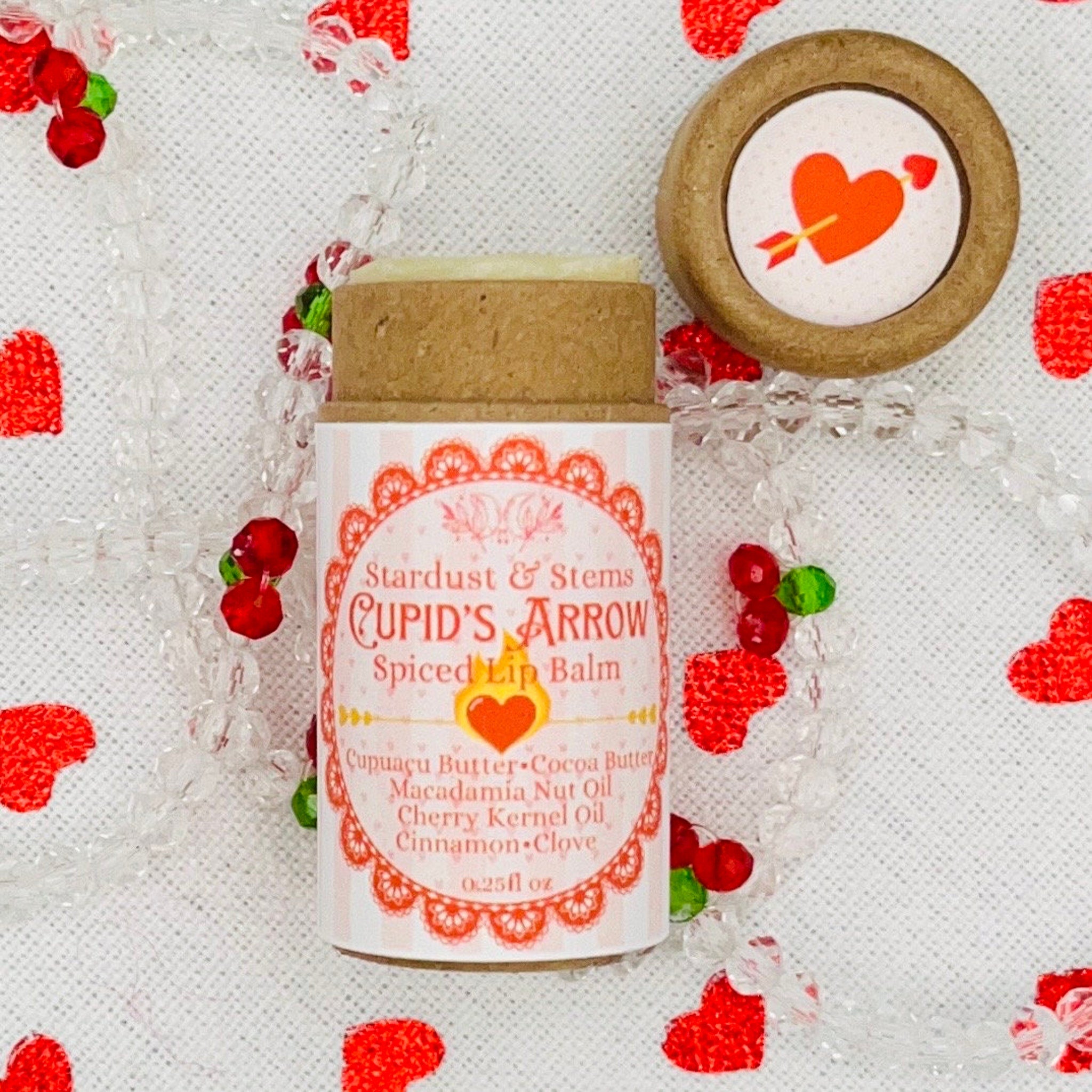 Lip balm tube with "Cupid's Arrow" label, brown cardboard, and white background with red hearts