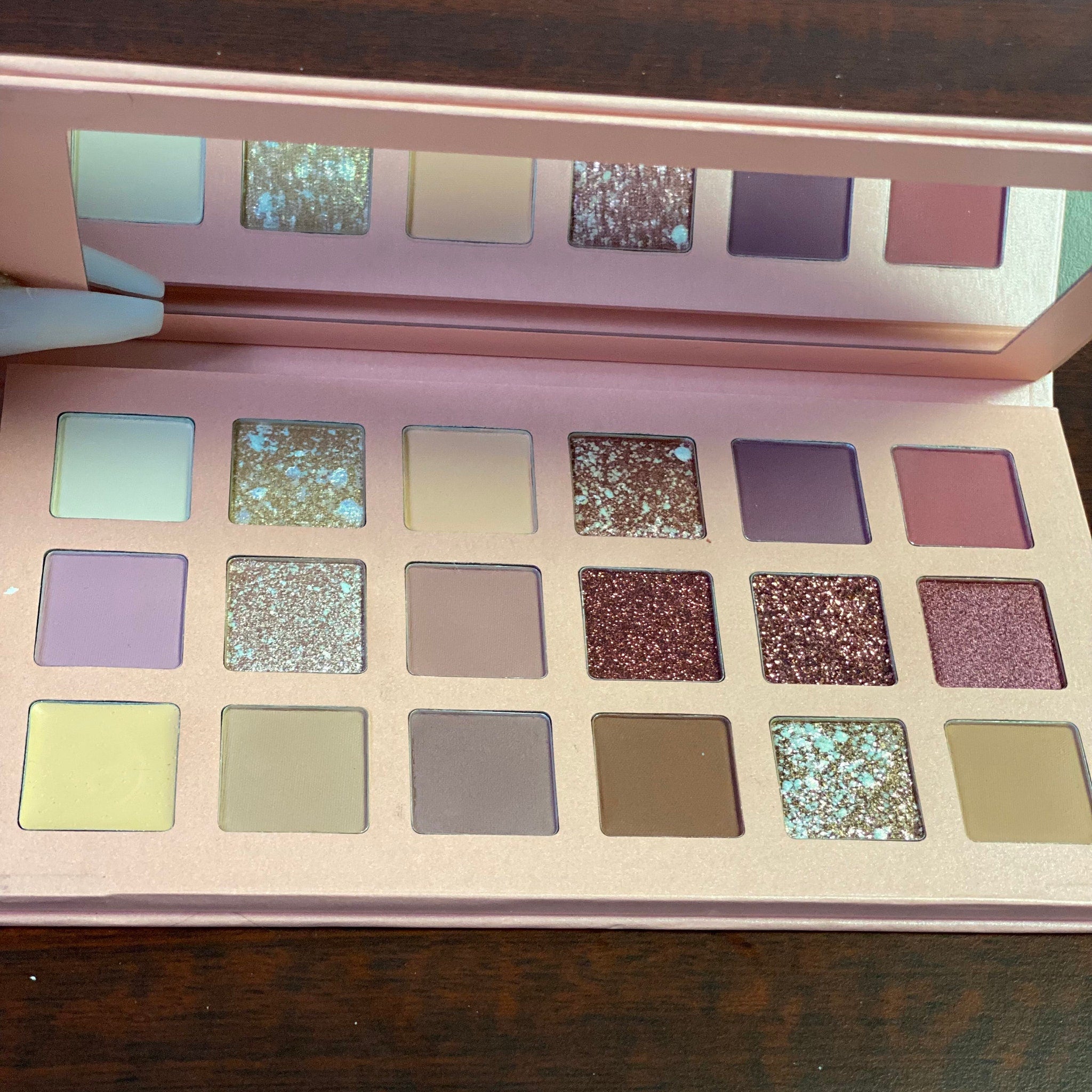 Close-up of shimmering rose gold eyeshadow palette with warm metallic hues and smooth powder texture