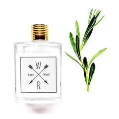 Glass bottle with gold cap, white label, and green leaves on white background
