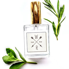 Perfume bottle with gold cap, clear glass, and "Luxe Dew" label with arrows