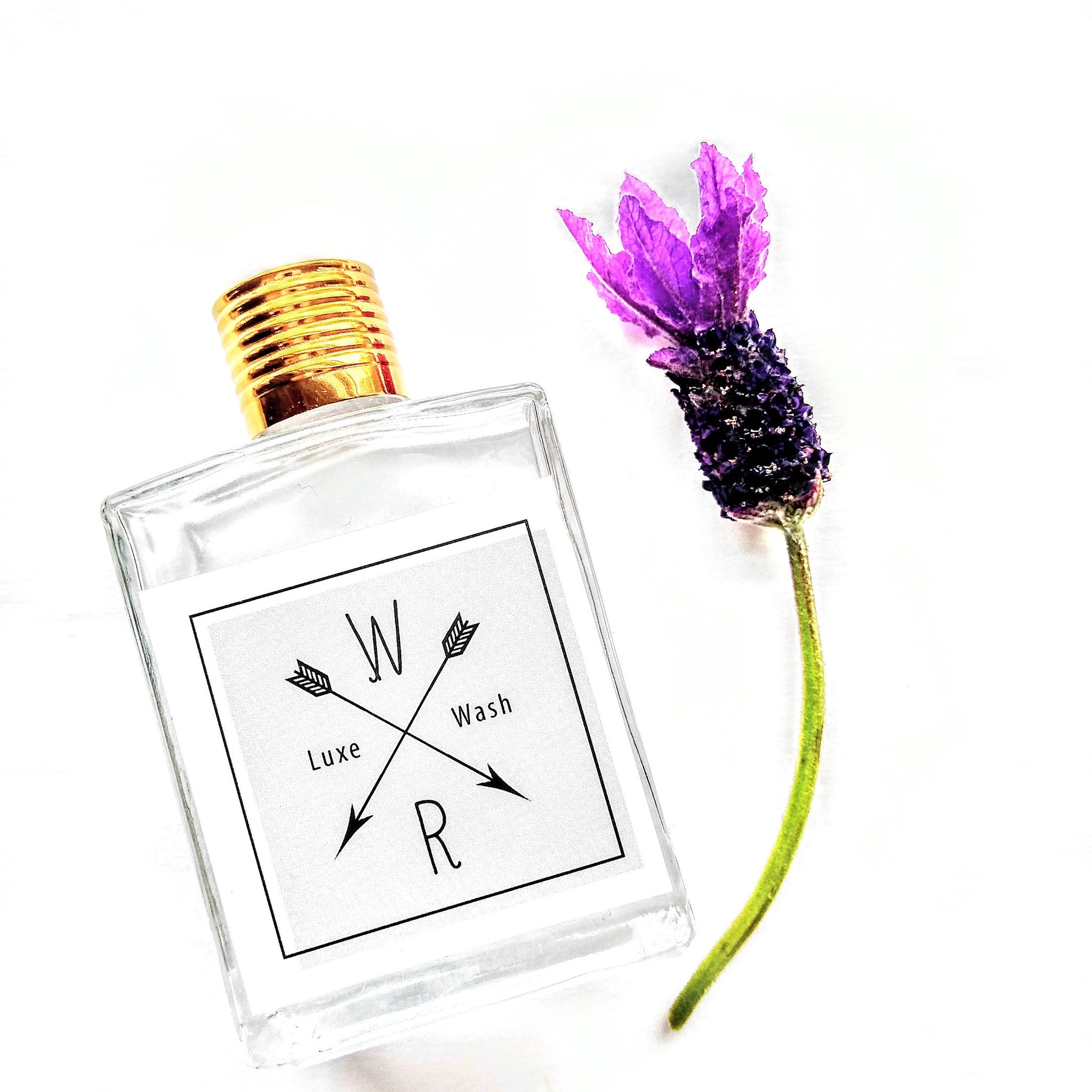 Perfume bottle with gold cap, clear glass, and "W Wash R" label with purple flower