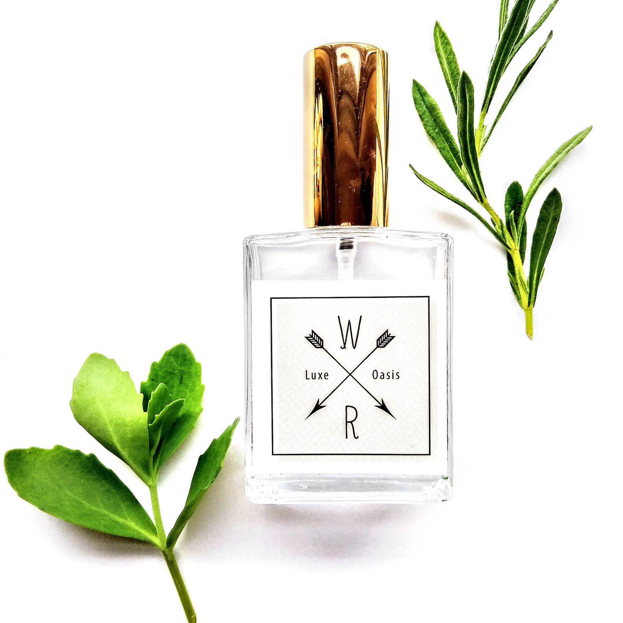 Perfume bottle with gold cap, clear glass, and "Luxe Oasis" label with green leaves surrounding