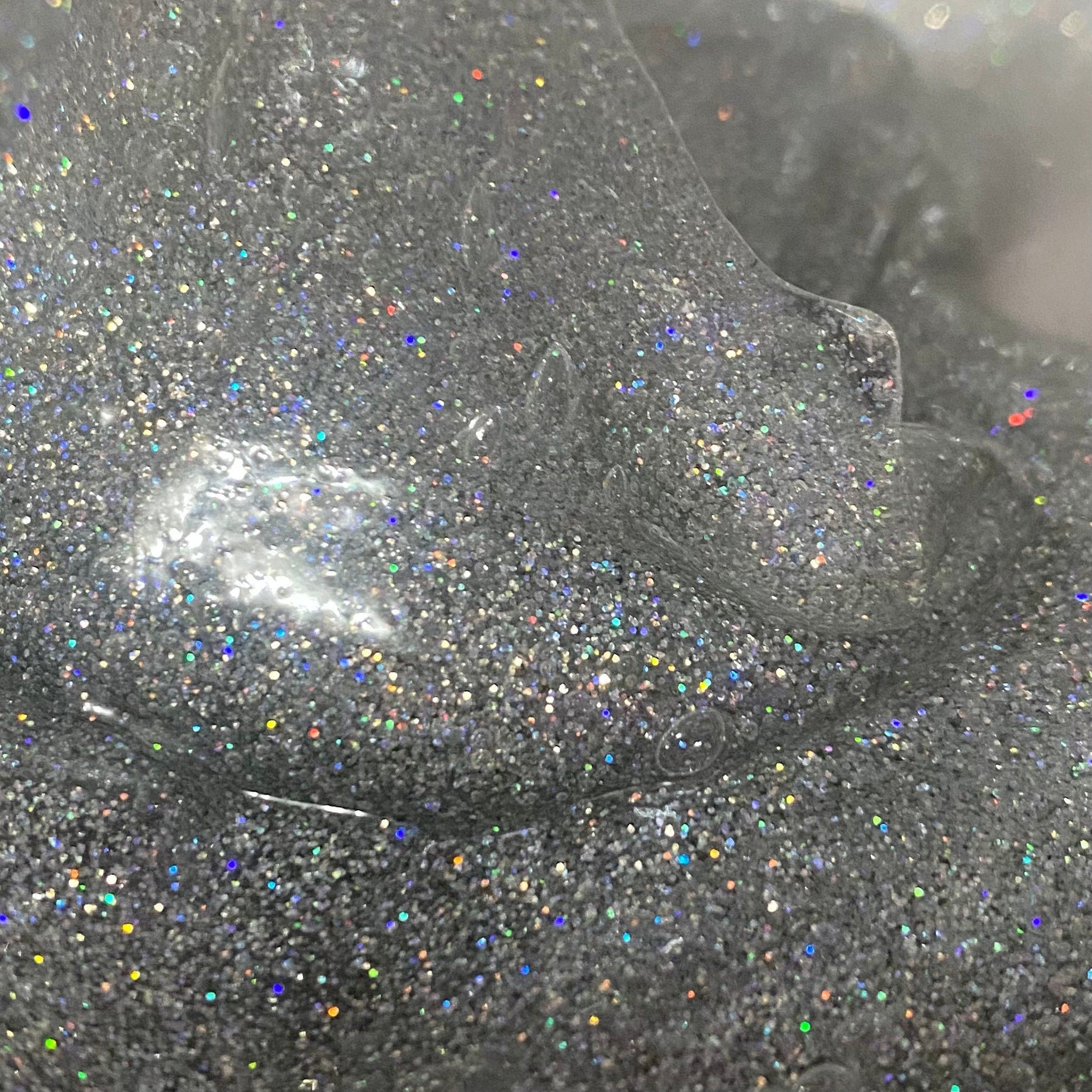 Glittery silver slime with iridescent sparkles close-up shot, showing texture and detail