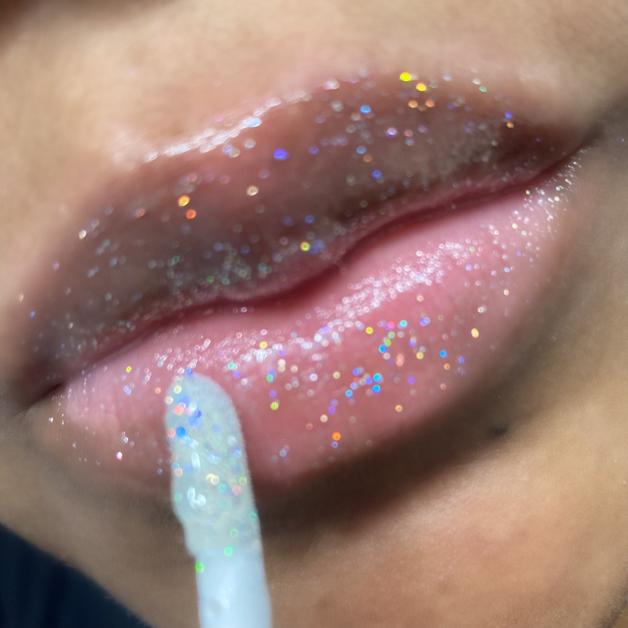 Lip gloss with iridescent glitter, applied to lips with applicator wand