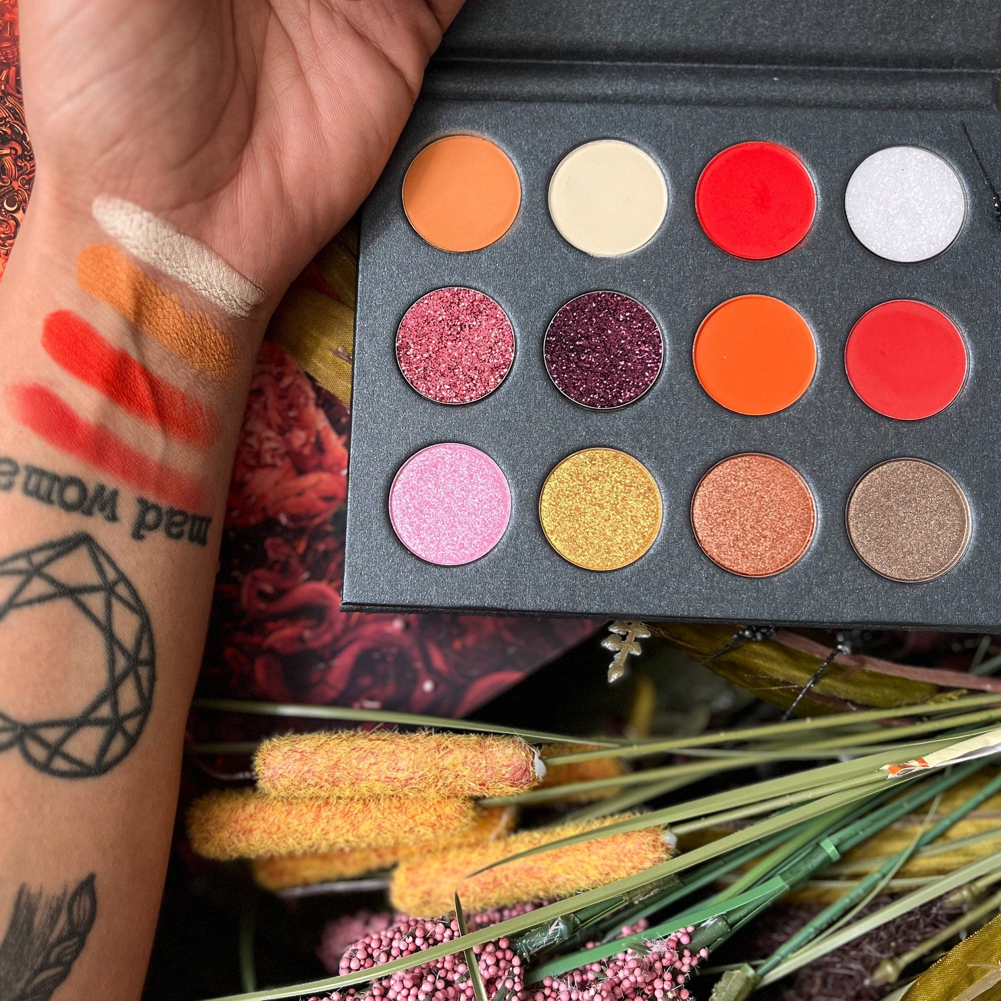 Bryce Quinlan eyeshadow palette open on table, showcasing matte, shimmer, and glitter shades in warm neutrals and golds