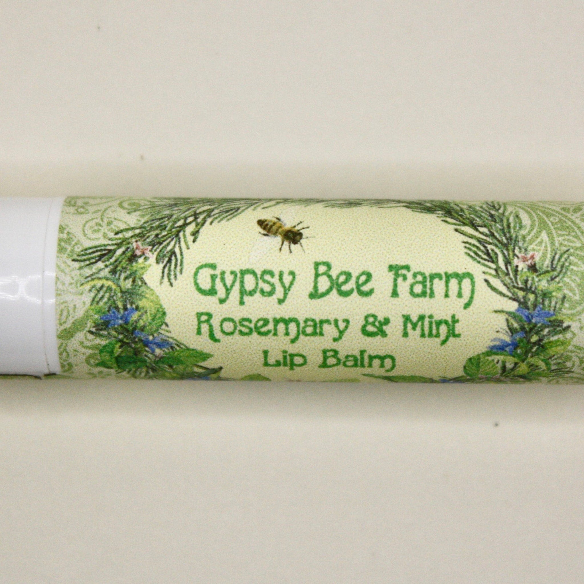 Lip balm tube with green floral pattern, "Gypsy Bee Farm" text, and white cap end