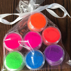 Close-up of seven vibrant neon matte eyeshadows in rainbow colors with smooth pigment texture