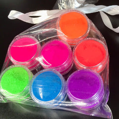 Side view of seven vibrant neon matte eyeshadows in round pans with UV glow pigments, showcasing color intensity