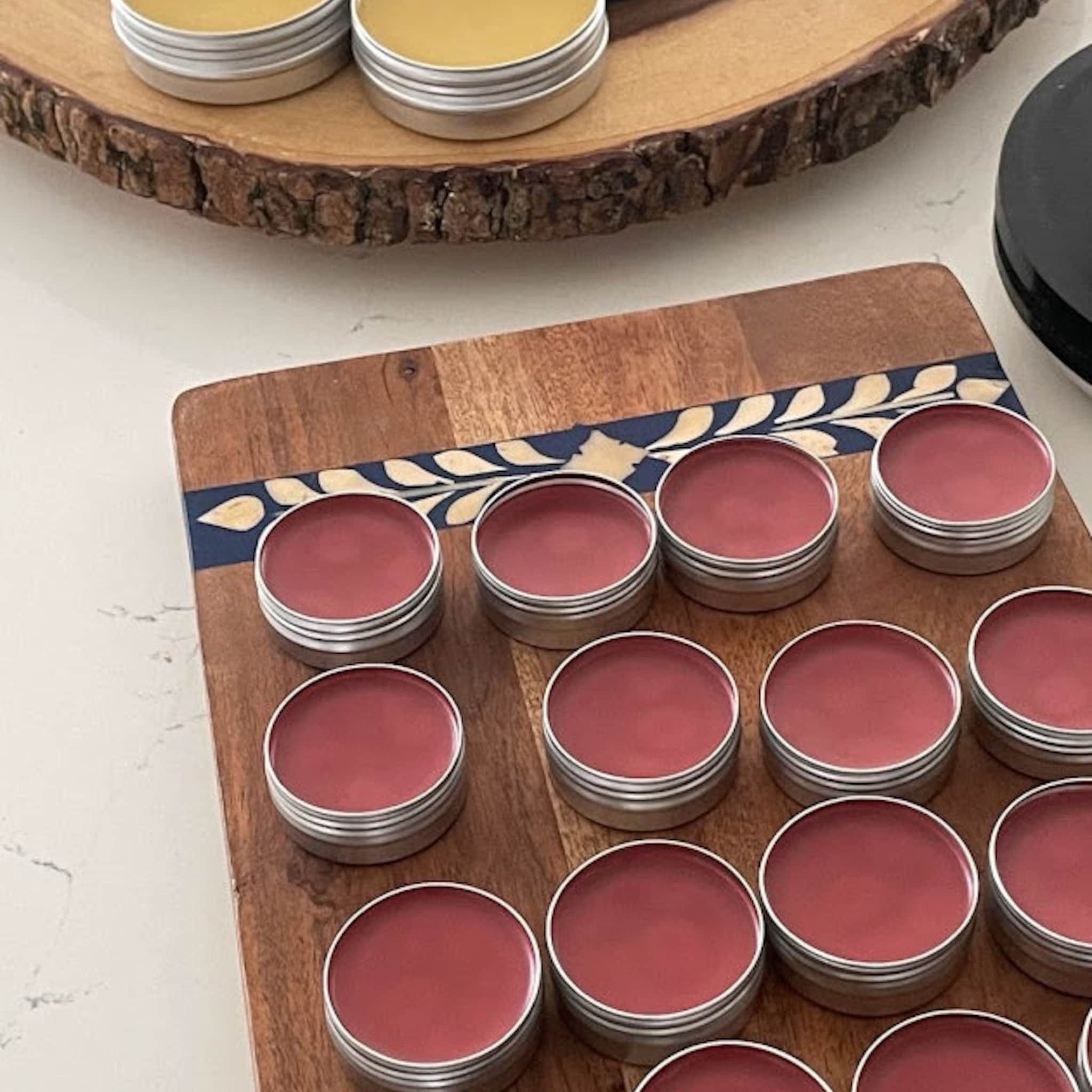 Lip balms in silver tins with red balm on wooden boards
