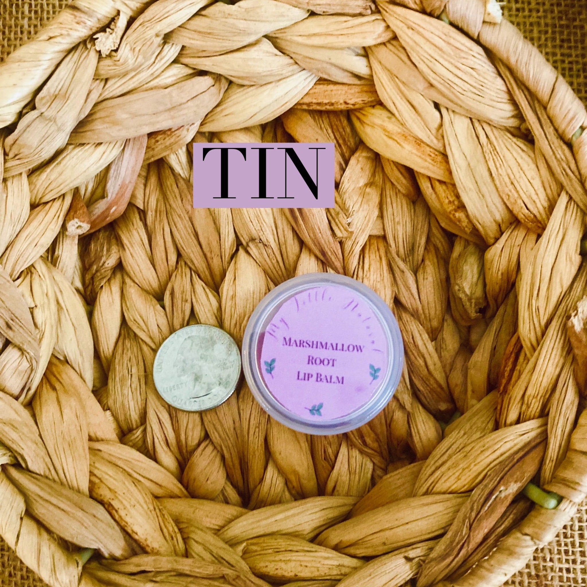 Lip balm tin with purple label, quarter, and woven straw background
