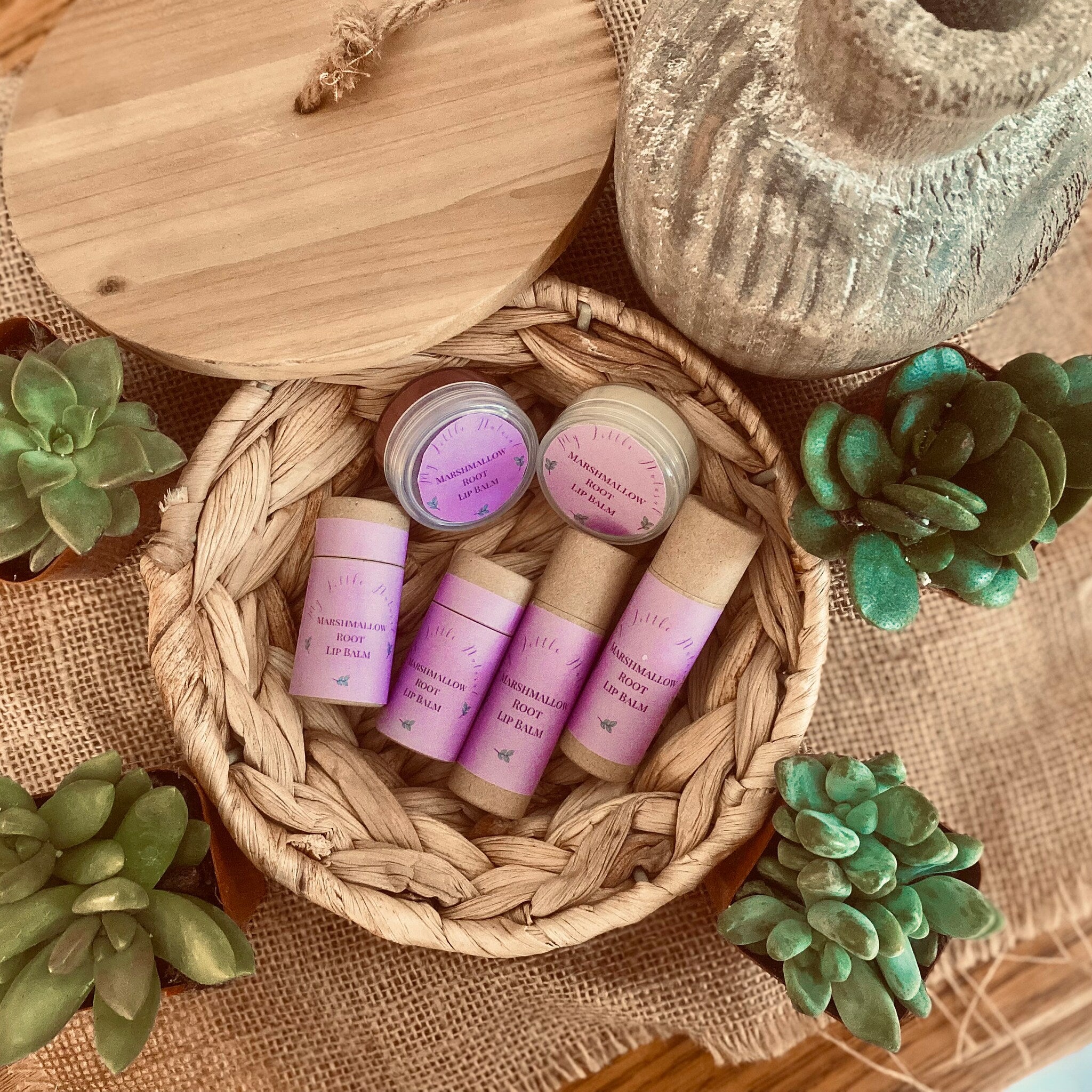 Lip balm tubes with purple labels and brown paper, in a woven basket with My Little Naturals branding