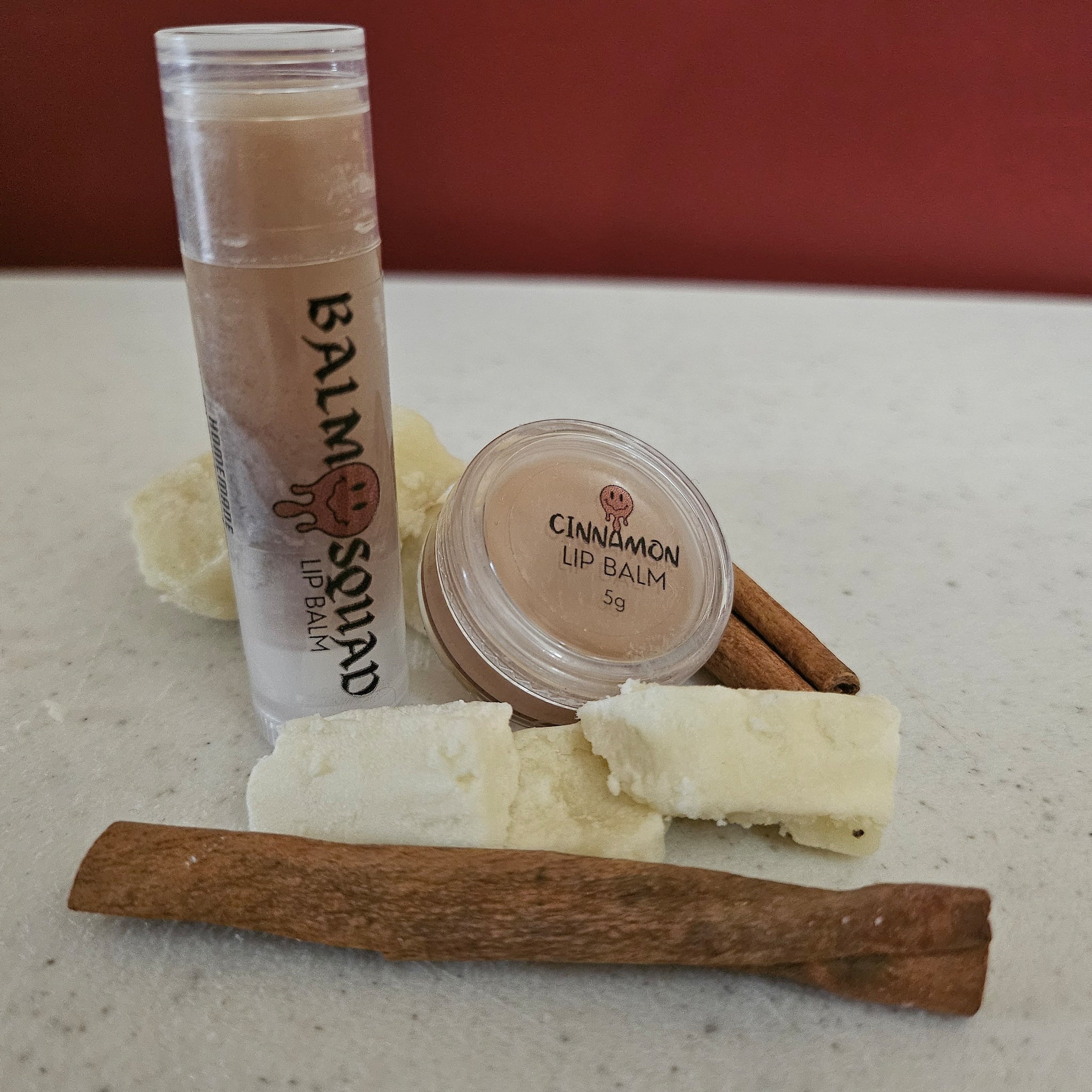 Lip balm in clear tube and jar with brown cinnamon sticks and white blocks