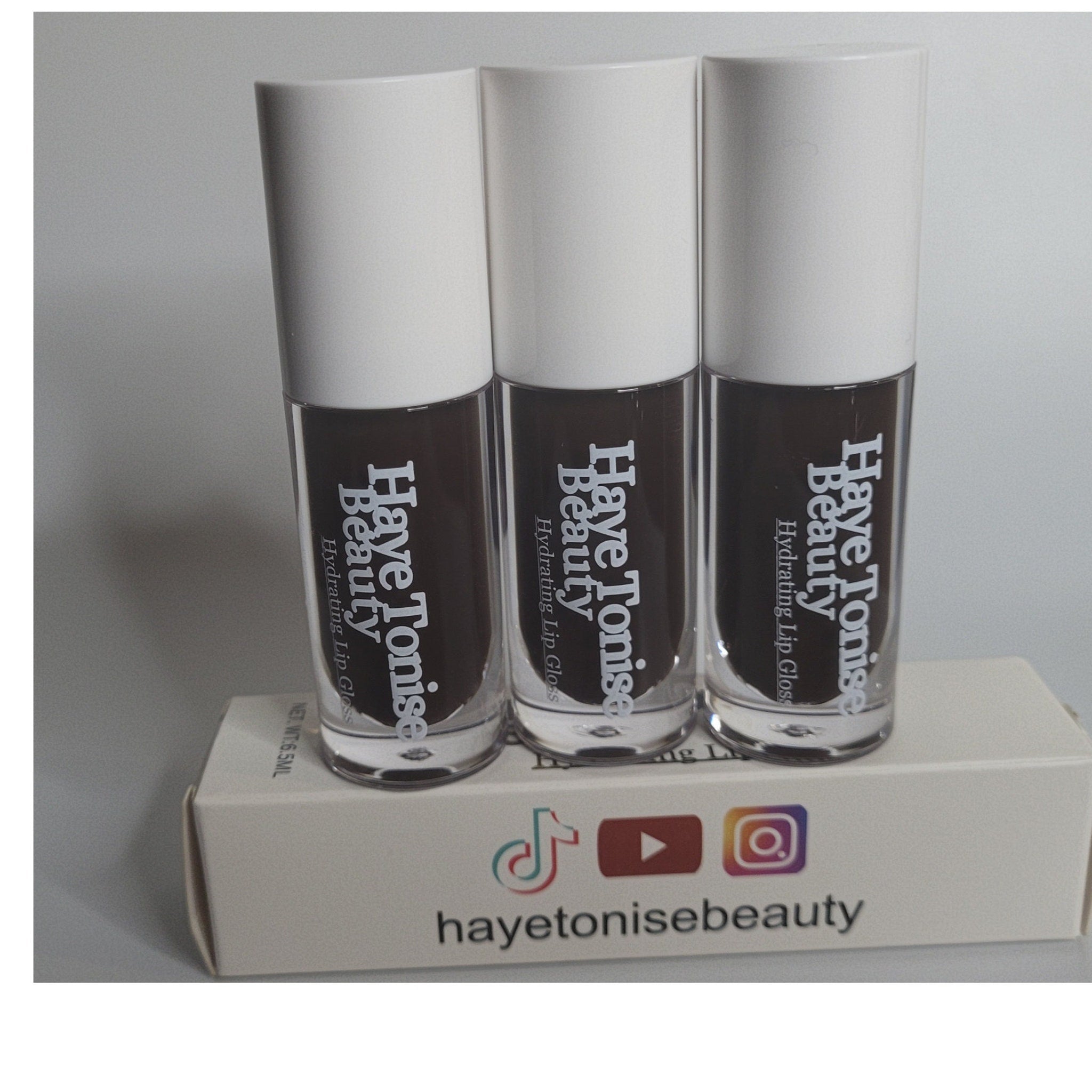 Lip gloss tubes with white caps, brown gloss, and Haye Tonise Beauty branding on a white box