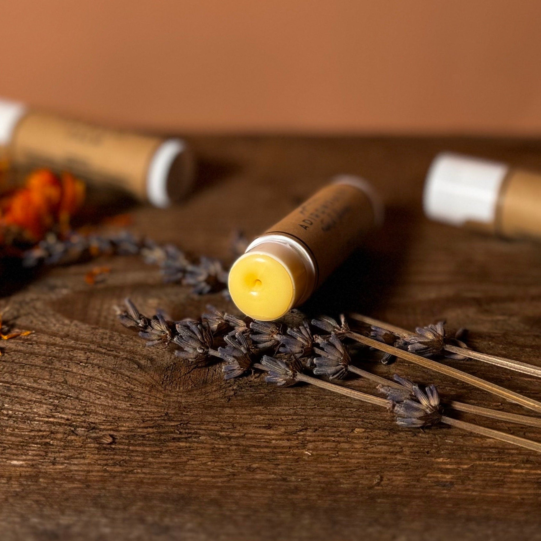 Lip balm tube with yellow balm, brown paper, white cap, and Adirondack Natural Skincare text