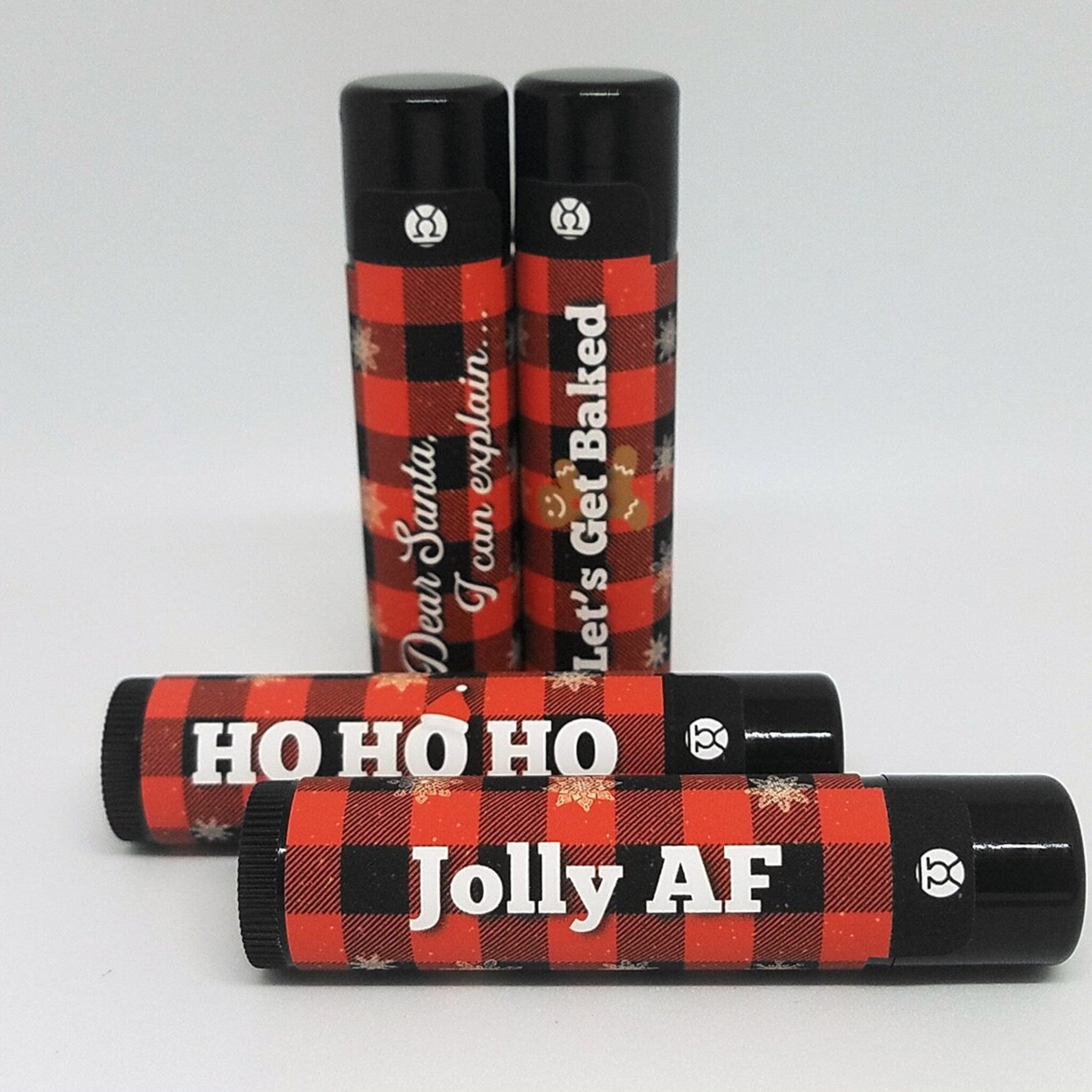 Christmas lip balms with red plaid pattern, black caps, and Venus Complete logo