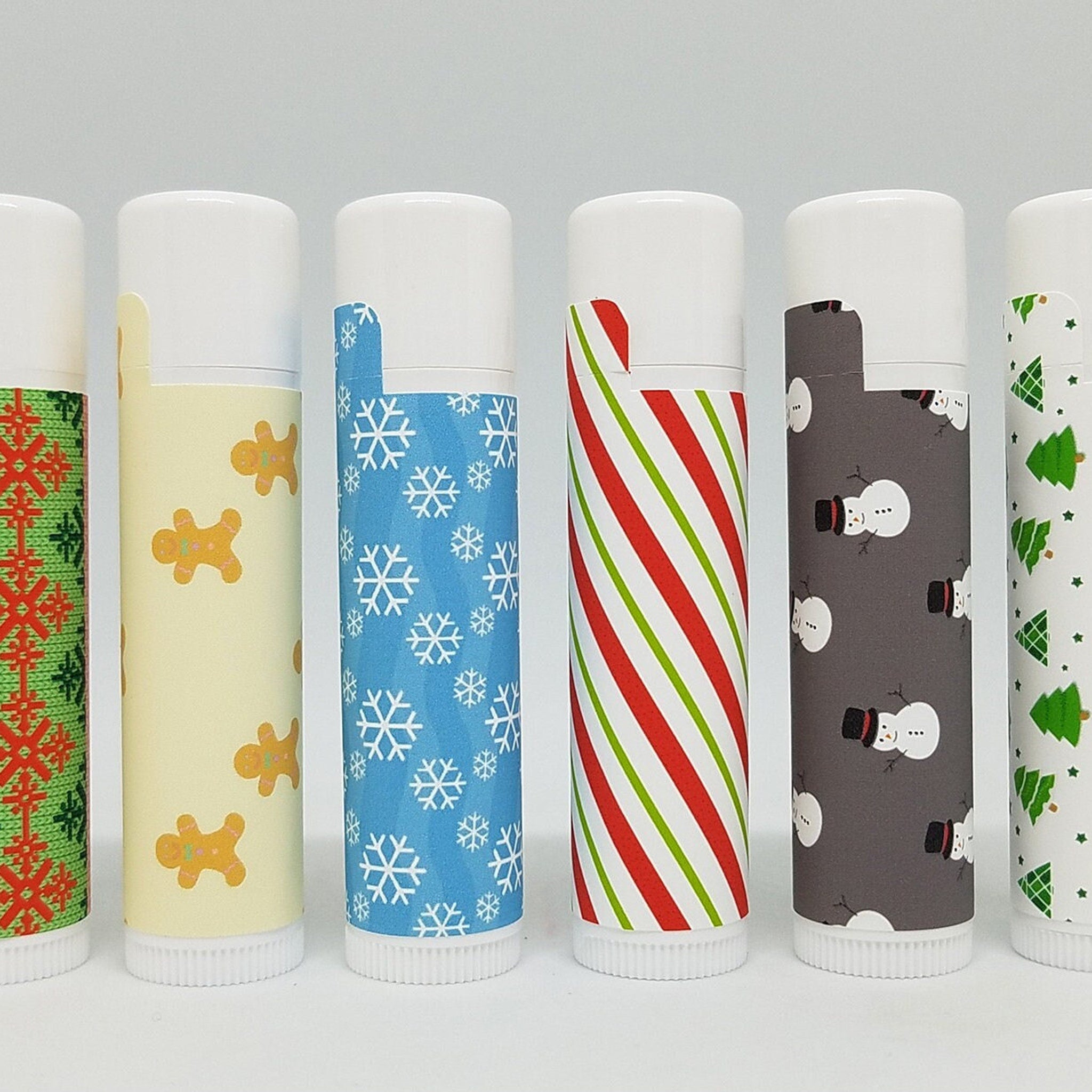 Christmas lip balms with various patterns, white tubes, and white caps