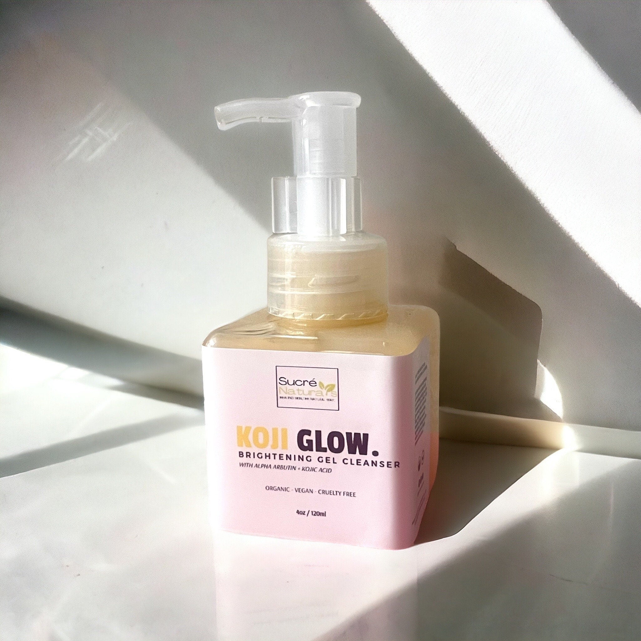 Brightening gel cleanser bottle with clear pump, pink label, and yellow liquid inside Sucré Naturals bottle