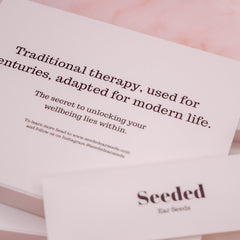 Seeded Ear Seeds branding on white paper with pink background, text about therapy and wellbeing