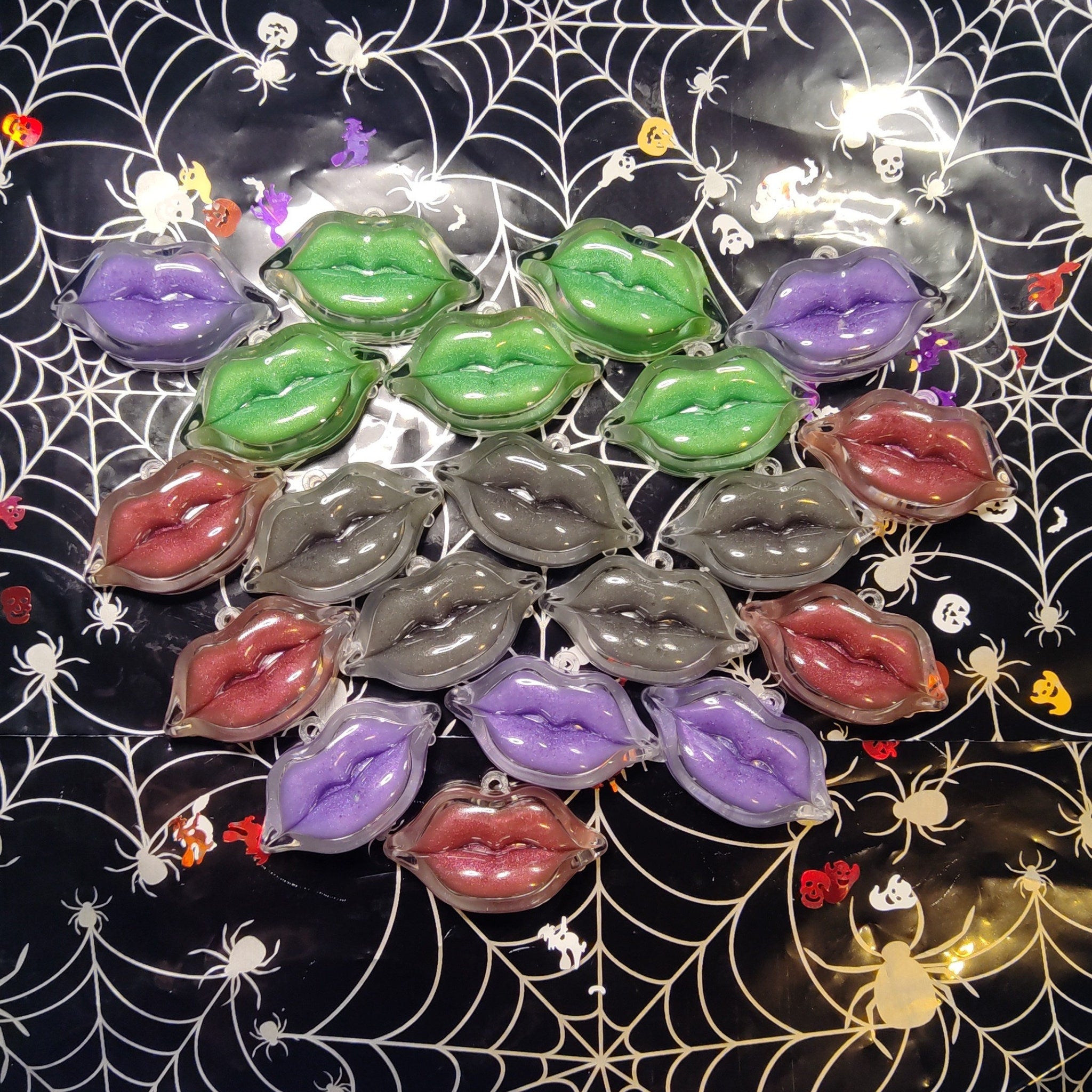 Lip-shaped ornaments in various colors, clear plastic, on spiderweb background