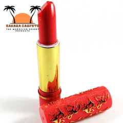 Red lipstick with gold tube and patterned red cap on white background