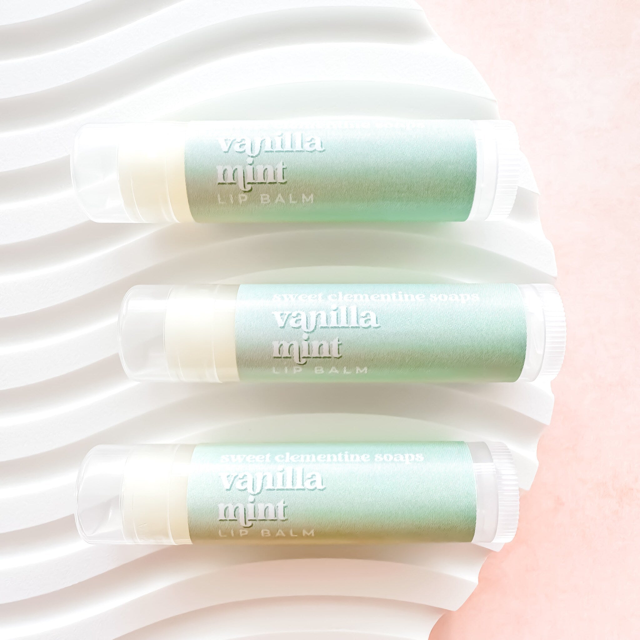 Lip balm tubes with mint green label, white text, and clear plastic casing