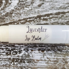 Lavender Lip Balm tube, white with script text, on textured wood surface