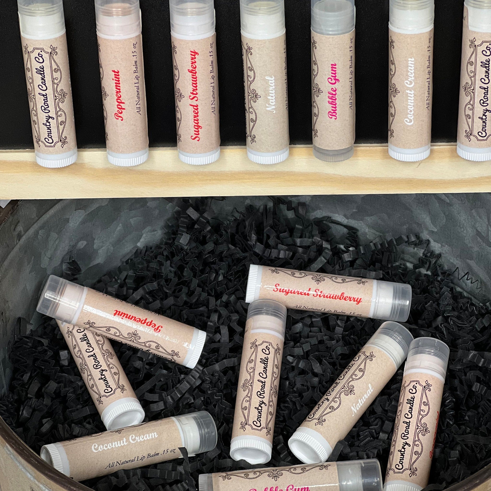 Lip balm tubes with beige paper labels, white caps, and various flavor names visible
