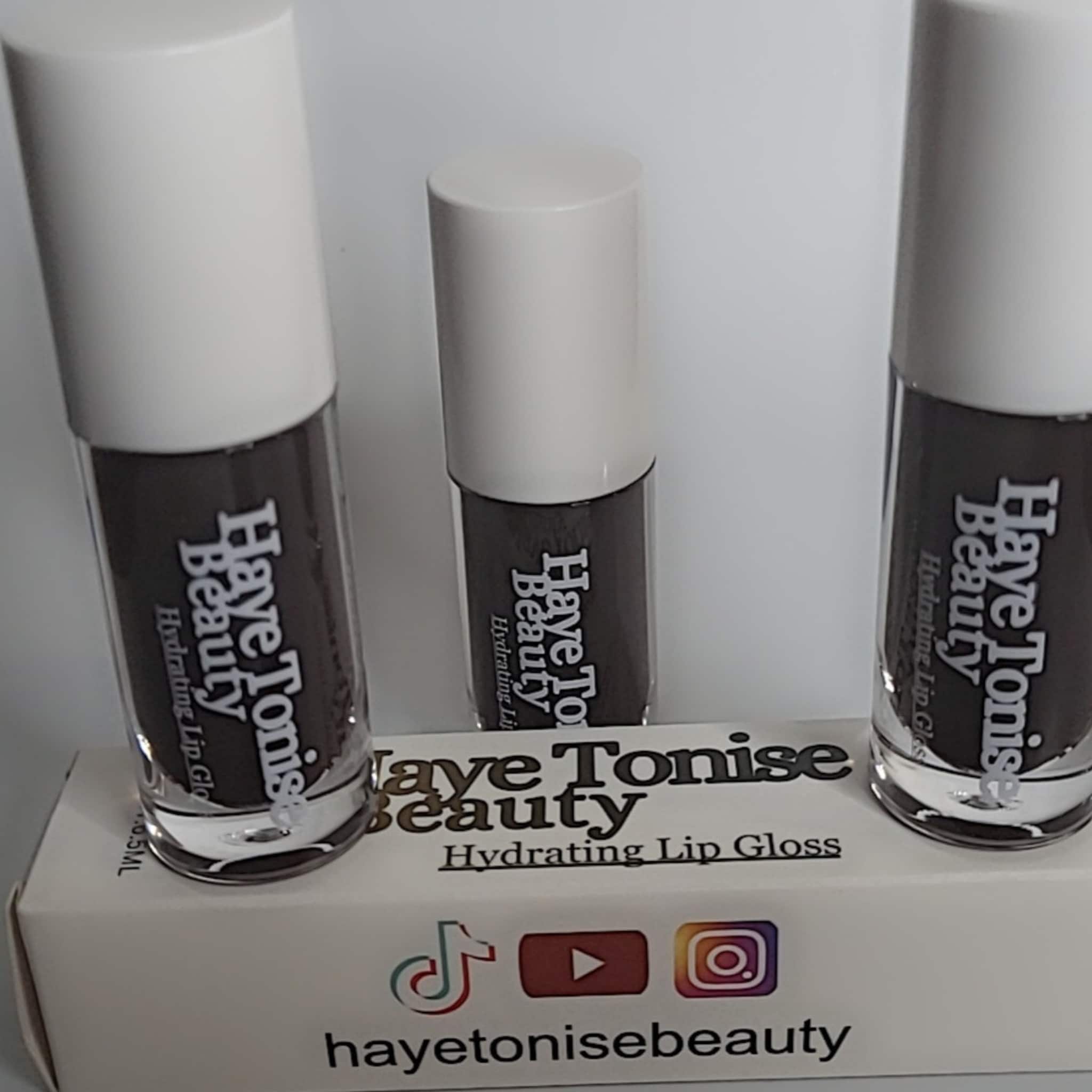 Lip gloss bottles with white caps, brown gloss, and Haye Tonise Beauty branding on display