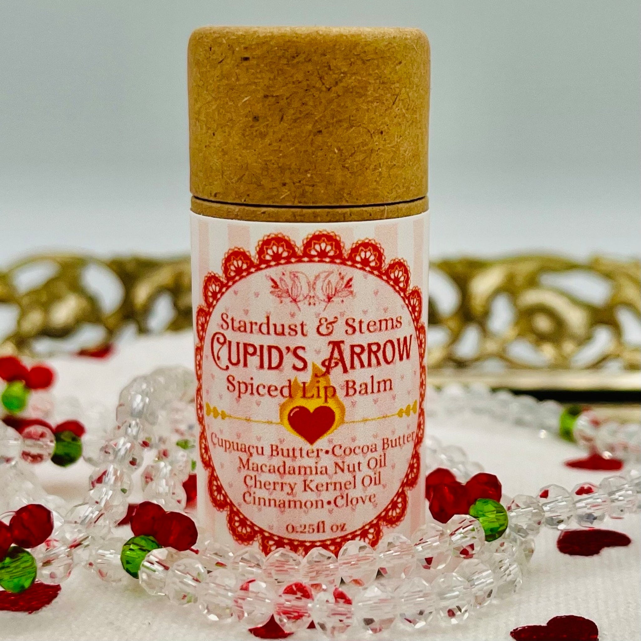 Lip balm tube with brown cap, pink and red label, and Stardust & Stems text on it.