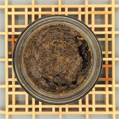 Brown paste in glass jar with textured surface and wooden grid background