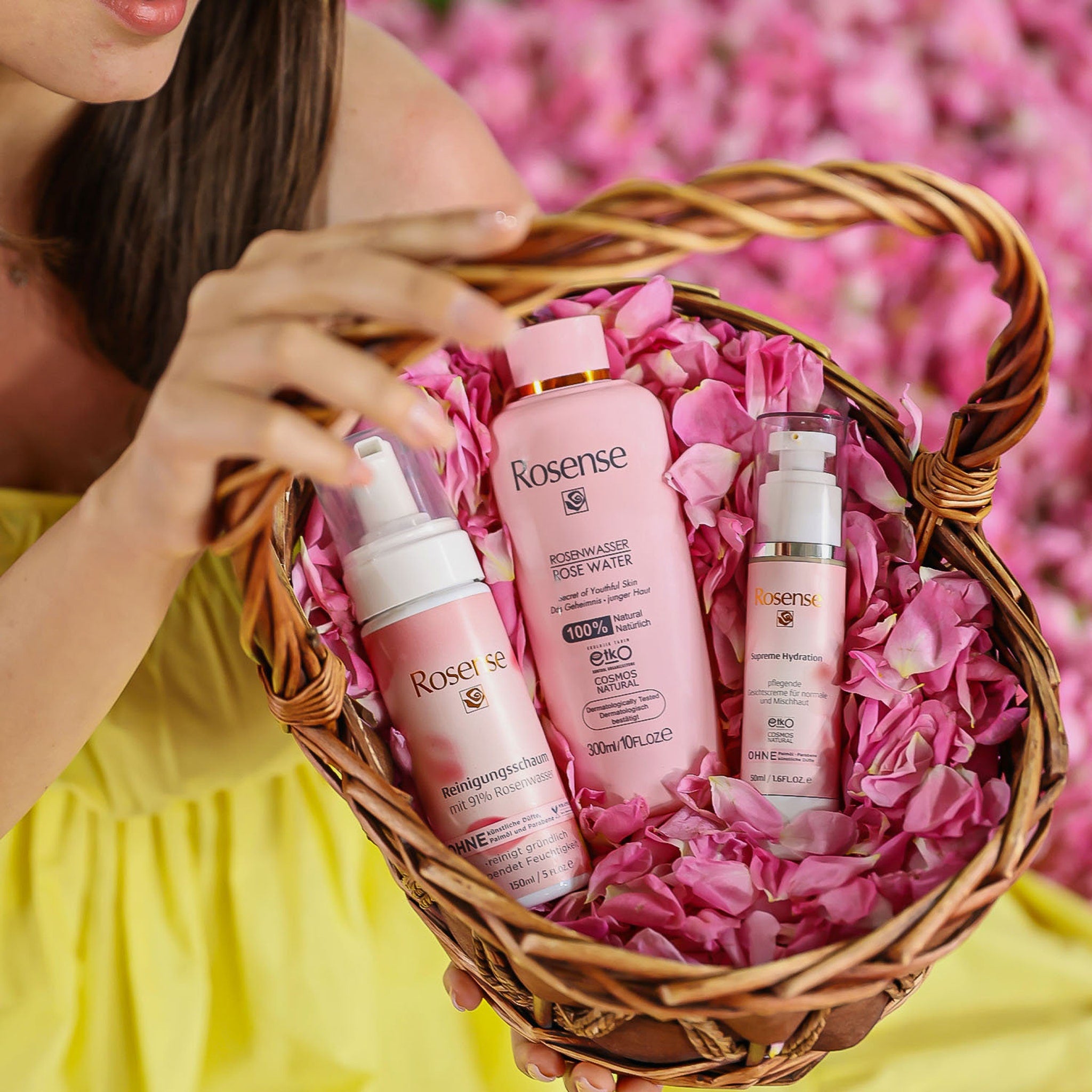 Rose water products in pink bottles with Rosense label inside a woven basket with rose petals
