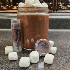 Lip balm with brown tint, clear tube, and BALM SQUAD text next to hot chocolate drink with marshmallows