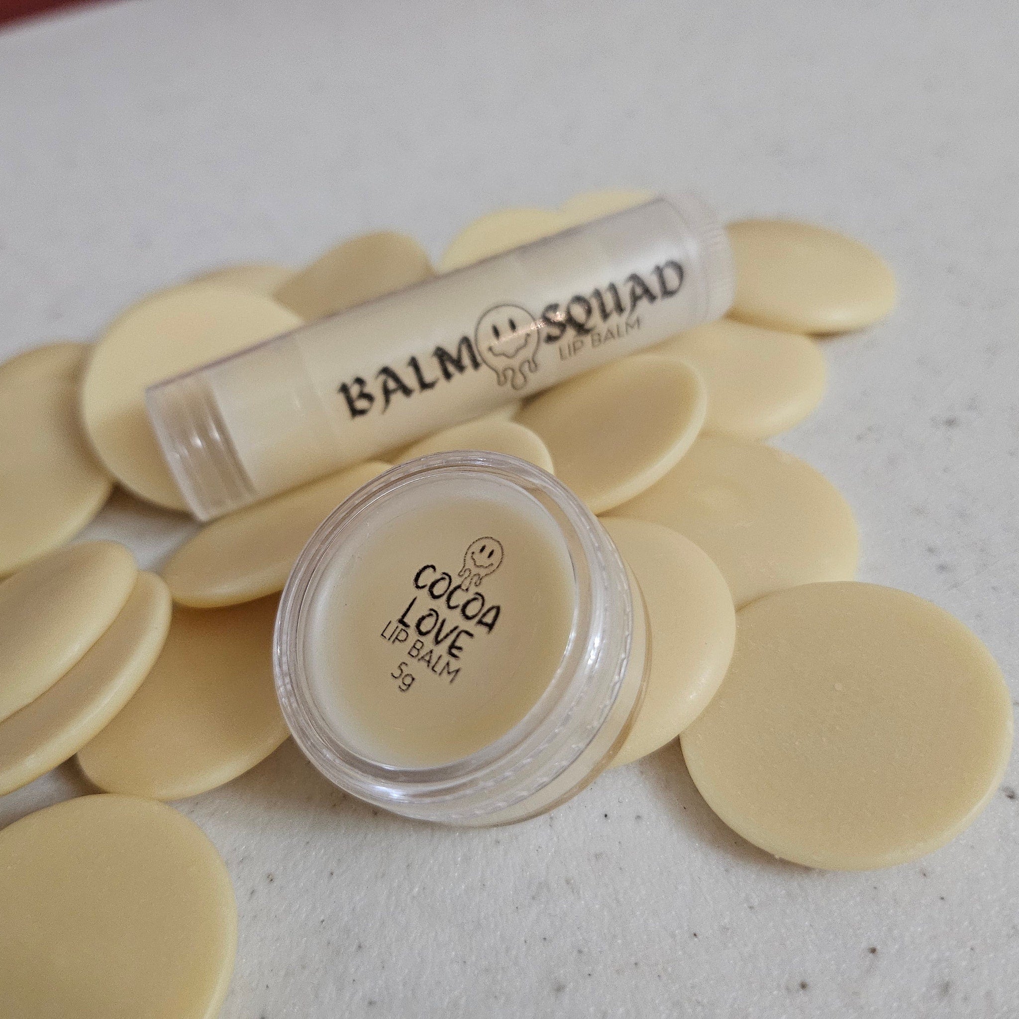 Lip balm with white cream color, clear container, and cocoa love text on a white surface with circles