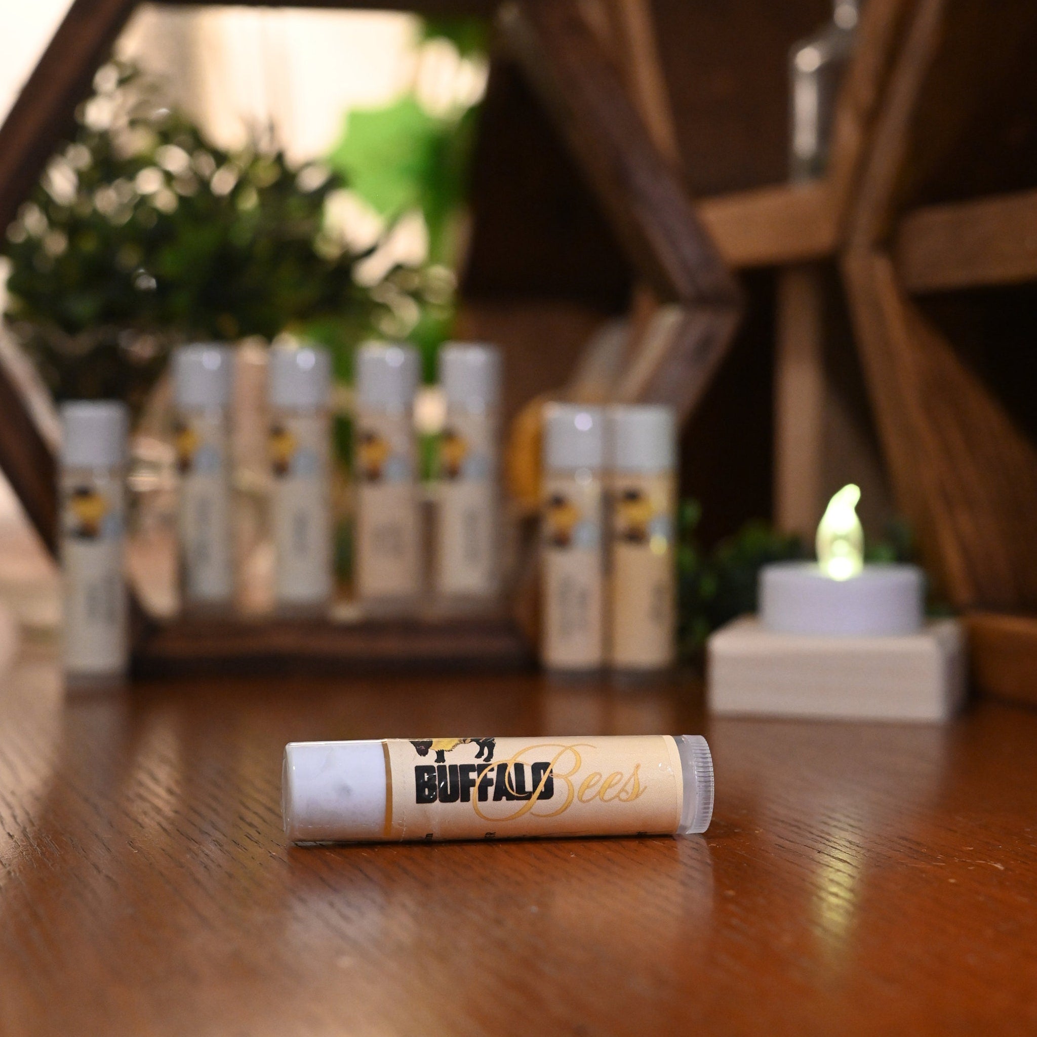 Lip balm tube with white, tan, and clear packaging, and Buffalo Bees logo on a wooden surface