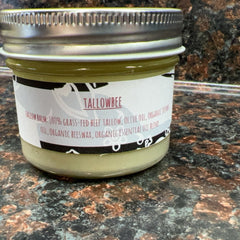 Tallow balm jar with silver lid, white label, and green contents, TALLOWBEE brand
