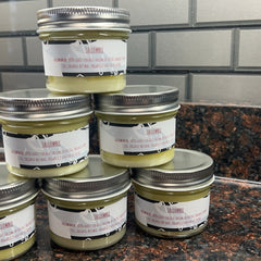 Tallow balm jars with silver lids, white labels, and yellow balm, TALLOWBEE brand visible