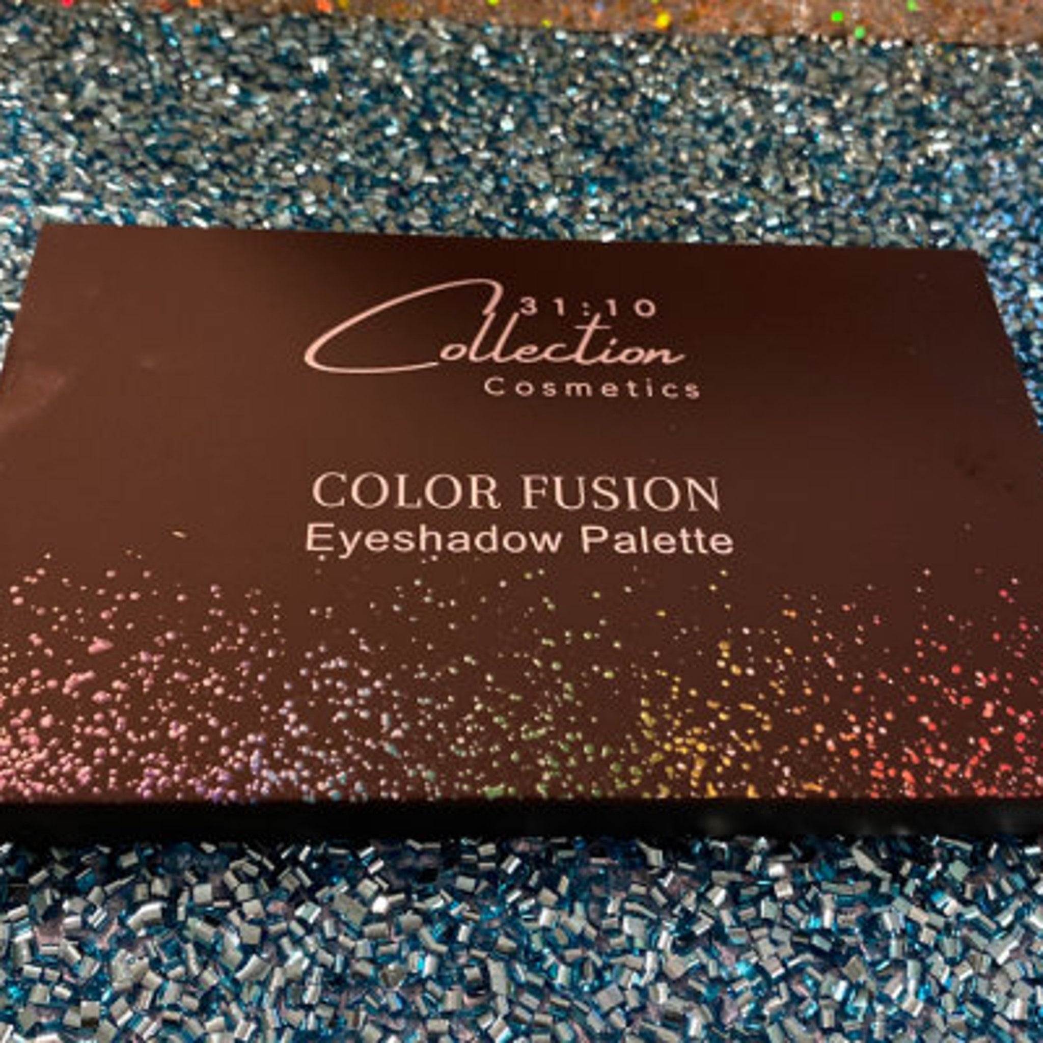 Close-up of pressed glitter eyeshadow palette showing vibrant multicolor shimmer pigments in circular pans