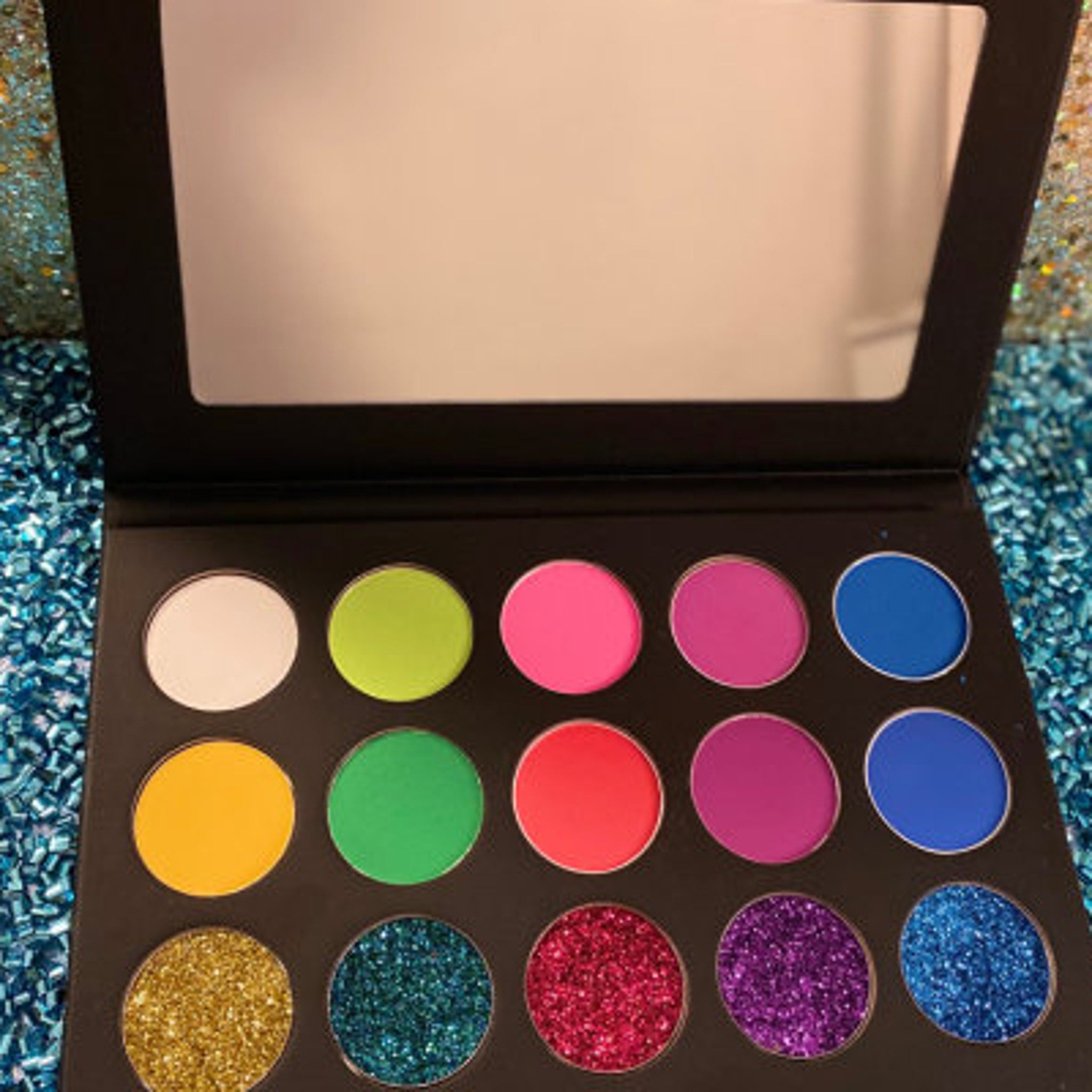 Open compact showcasing vibrant vegan eyeshadow palette with shimmering glitter fusion colors.