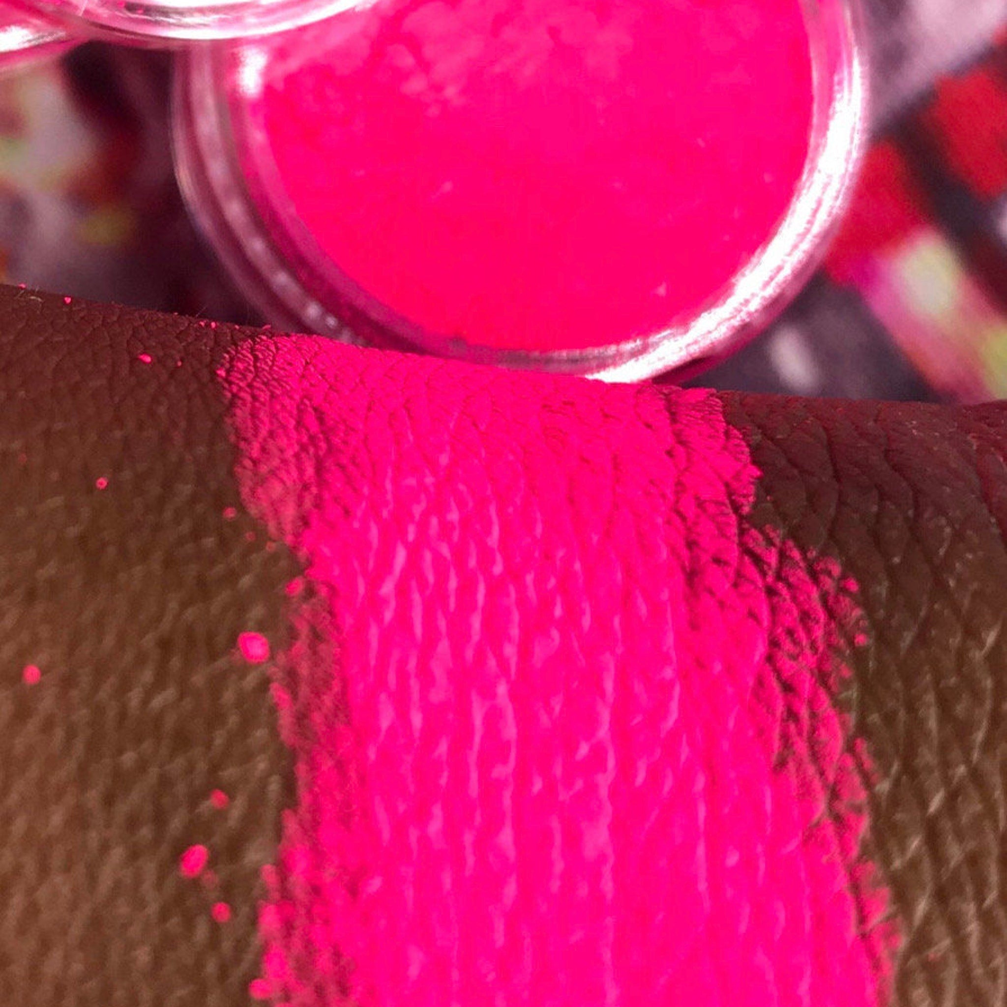 Close-up of vibrant neon pink matte eyeshadow pan with smooth pigment texture in sleek black compact