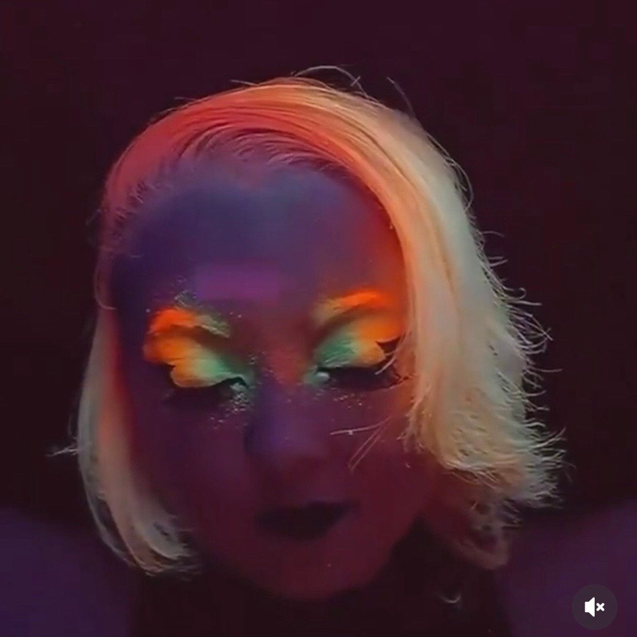 Side view of seven neon matte eyeshadow pans in vibrant rainbow colors with UV glow effect
