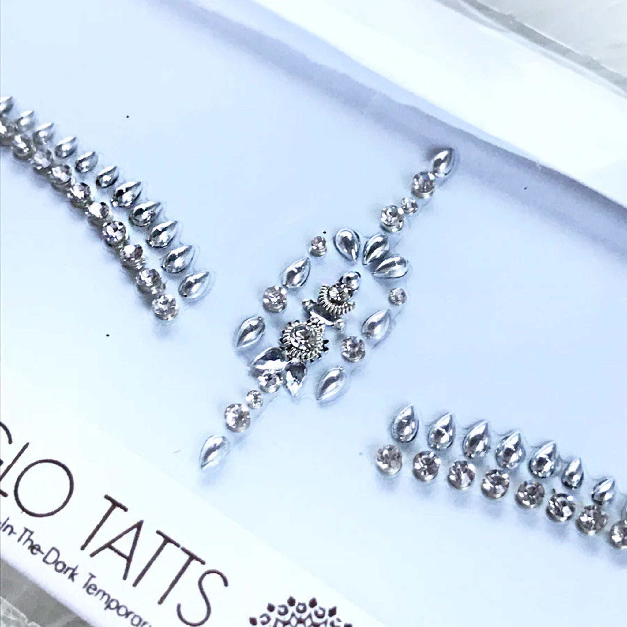 Body jewels with clear rhinestones and silver teardrop shapes on white background
