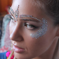 Face jewels with silver glitter and clear crystal accents, applied on face for a festival look