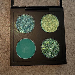 Close-up of lush green eyeshadow palette showing vibrant emerald and moss shades with smooth matte finish