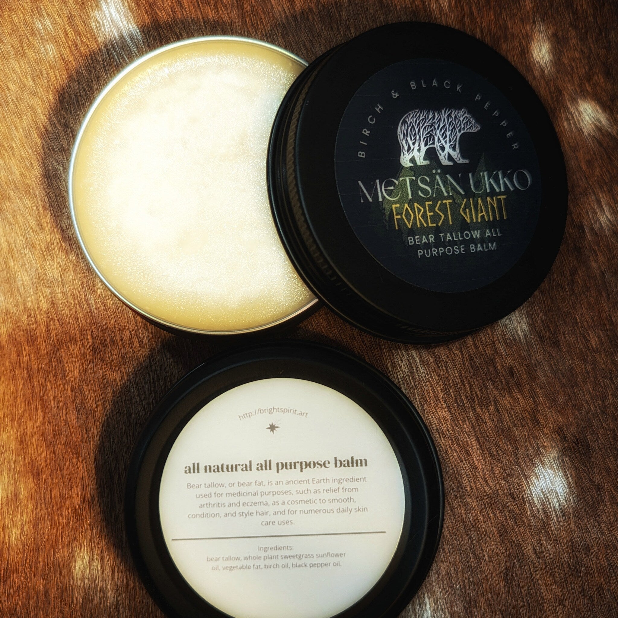 All purpose balm in black tin with white label, light yellow balm, and brown fur background