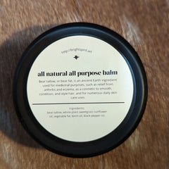 Balm jar with black rim and white label, on a textured brown surface, with text "all natural all purpose balm