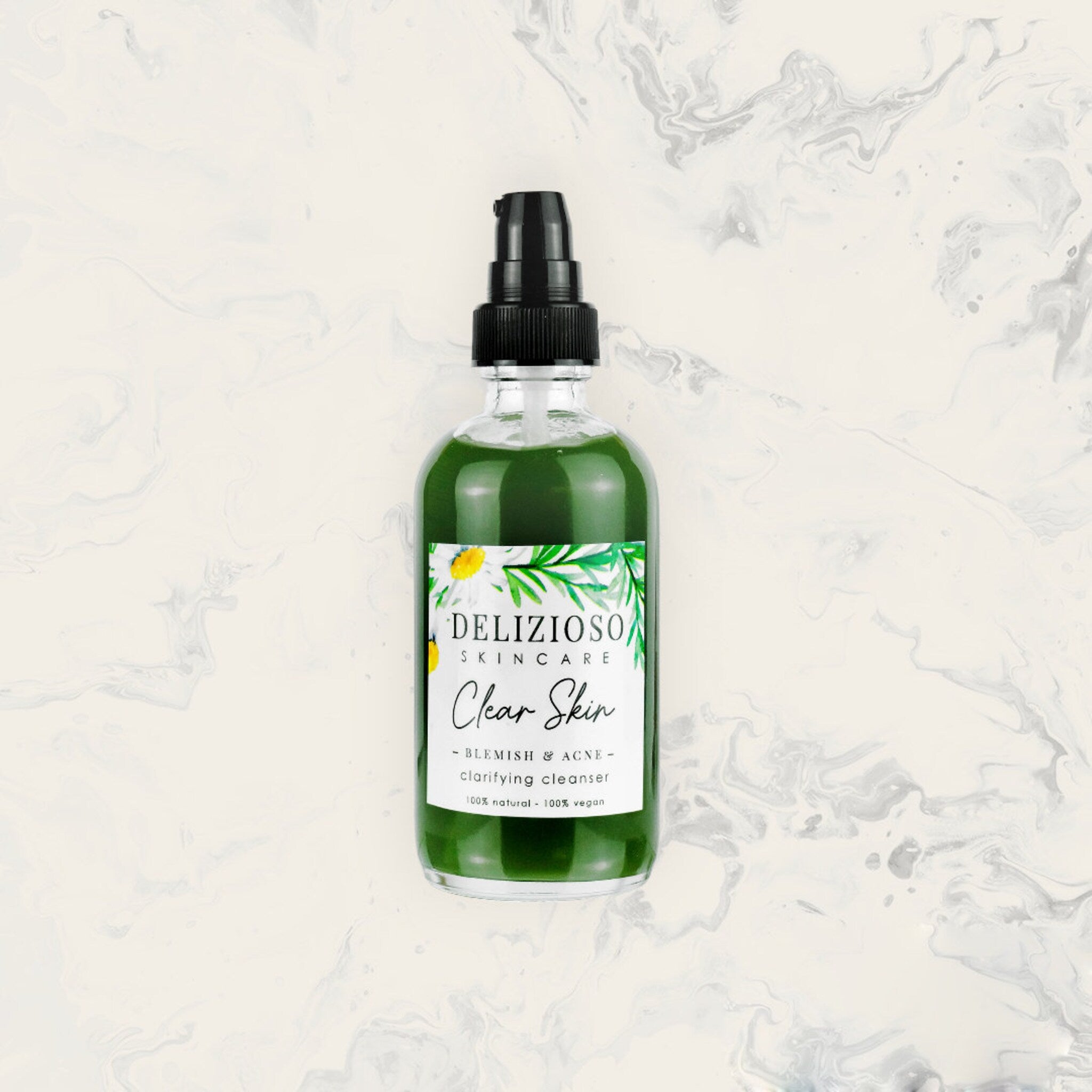 Facial cleanser bottle with green liquid, black pump, and Delizioso Skincare label on marble background