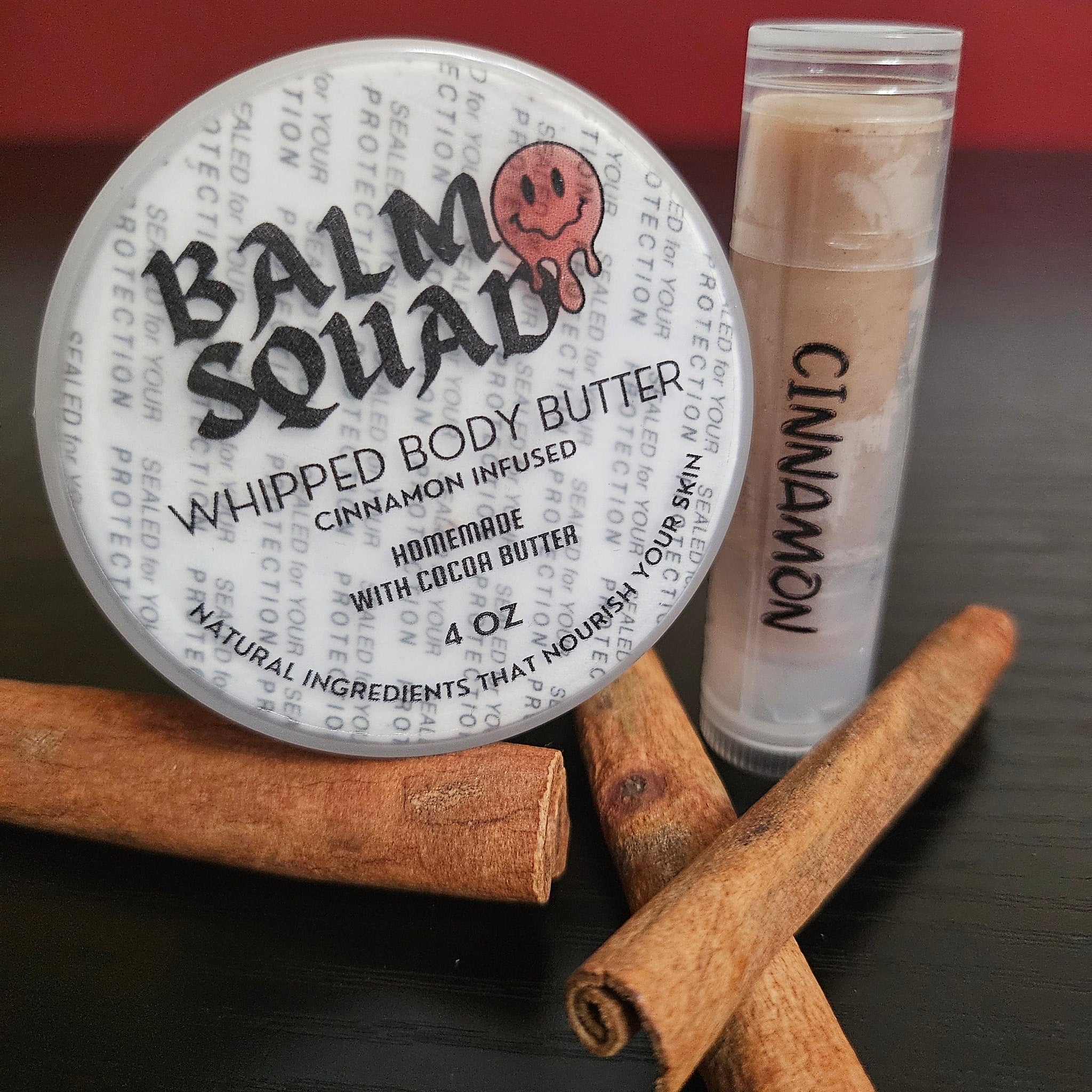Whipped body butter with cinnamon, white container with black text, and cinnamon sticks on black surface